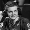 Ảnh đen trắng Cyanide mặc áo Fnatic, đeo tai nghe có micro và giơ nắm tay bên màn hình thi đấu.